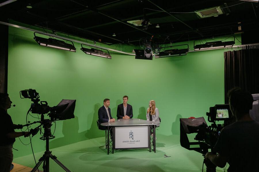Sports broadcasting students present in front of a green screen.